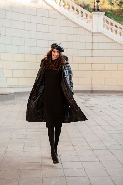 夹克时尚女人摆出冬秋时尚潮流黑色羽绒服和皮帽贝雷帽在古老美丽的街道穿着高跟鞋女人城市街头