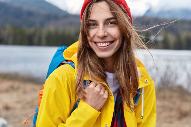 摆姿势微笑迷人的黄色外套女游客特写镜头 背着背包冒险徒步旅行者人类