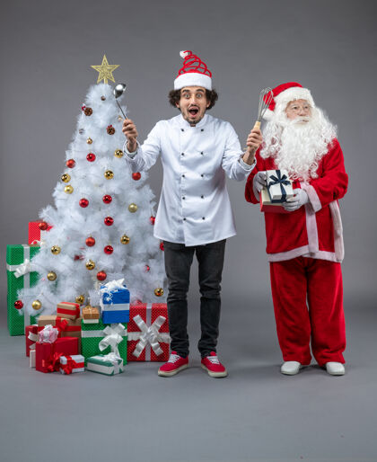 圣诞圣诞老人和男厨师在灰色墙上围着圣诞礼物的正视图圣诞老人十二月节日