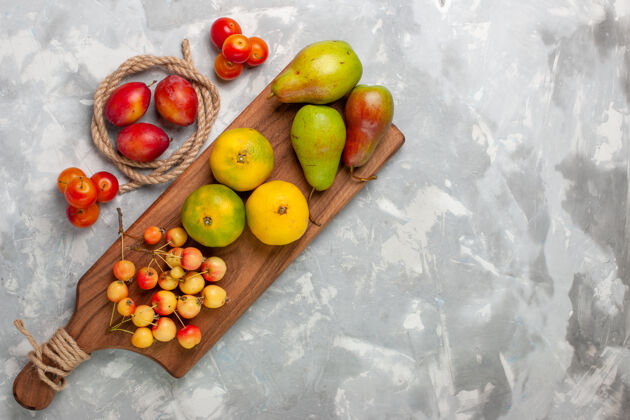 樱桃在浅白的桌子上俯瞰绿色的橘子和甜樱桃 李子和梨新鲜梨水果