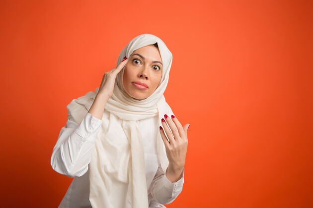 人争论 争论概念戴头巾的阿拉伯女人女孩的肖像 摆姿势红色工作室背景年轻情绪化的女人人类情绪 面部表情概念正面视图传统争论成人