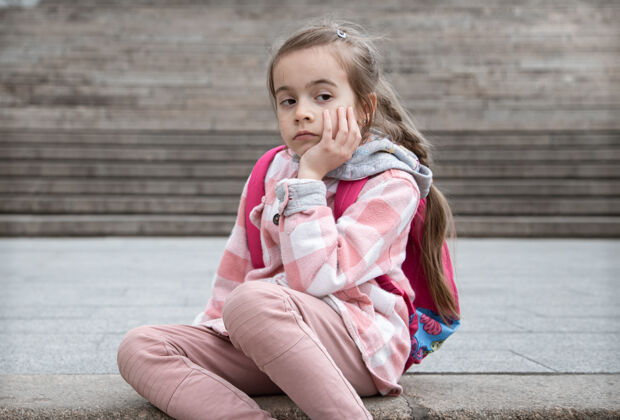 女生一个悲伤的小女孩背着书包 坐在楼梯上回到学校孩子女孩可爱