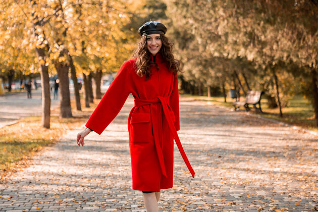 苗条迷人的时尚微笑的女人卷发漫步在公园穿着温暖的红色外套秋季时尚 街头风格 戴贝雷帽装束漂亮休闲
