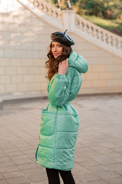 街头风格时尚女人摆出冬秋时尚潮流蓝色羽绒服和帽子贝雷帽在古老美丽的街道秋天时尚户外