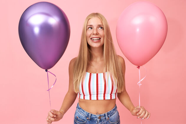女人可爱可爱的学生女孩手持两个金属氦气球 庆祝生日 玩得开心年轻无忧无虑情人节