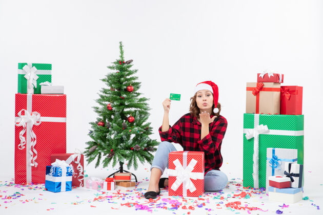 雪正面图：年轻女子围坐在白墙上 手里拿着绿色的银行卡圣诞快乐人人