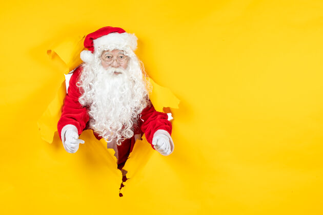 人圣诞老人透过撕破的黄色墙壁看的正视图通过服装快乐