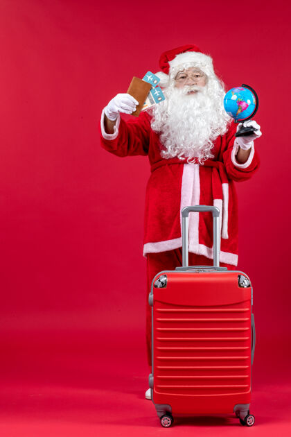 服装圣诞老人的前视图 带着包 拿着票 准备在红墙上旅行乐趣前面节日