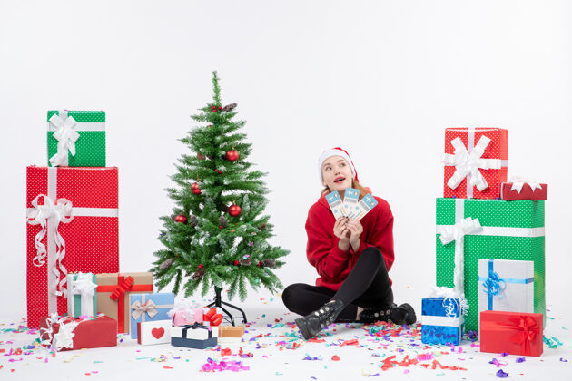 礼物前视图年轻女子围坐在白墙上拿着飞机票的礼物圣诞树快乐人