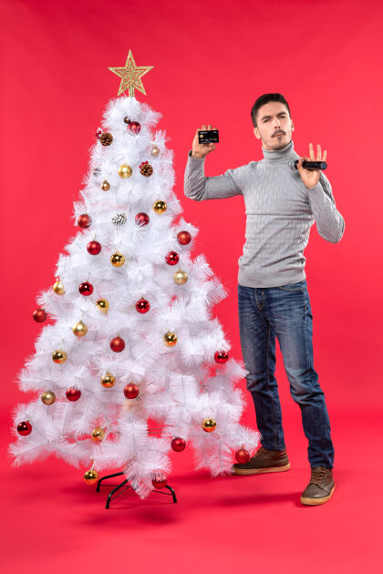 圣诞圣诞气氛 微笑的年轻人站在装饰好的圣诞树旁 拿着麦克风和电话 谈论着一些事情红色一些东西说话