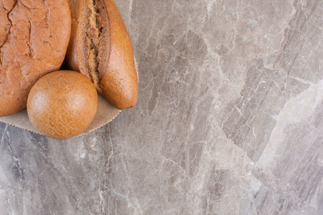 顶部视图各式各样的面包放在大理石木板上烘焙面粉顶部