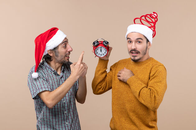 闹钟正面图两个男人一个拿着闹钟 另一个在米色背景上讲着什么男人微笑时钟