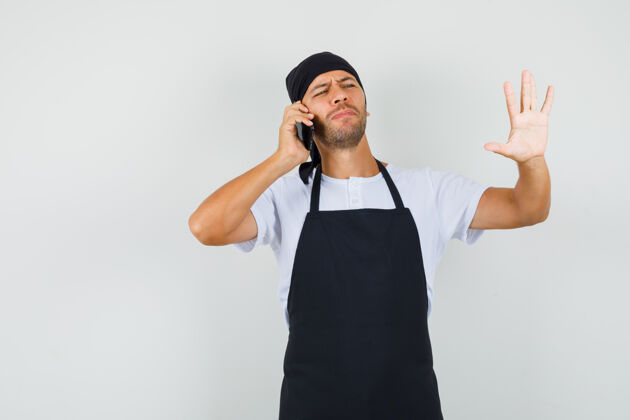 挥手面包师在讲手机 在t恤衫上显示停止的手势美味专业工人