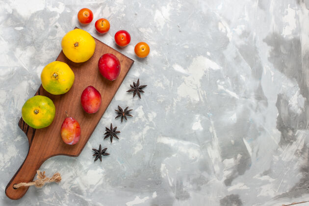 苹果在浅白的桌子上俯瞰新鲜的酸橙和李子新鲜水果李子