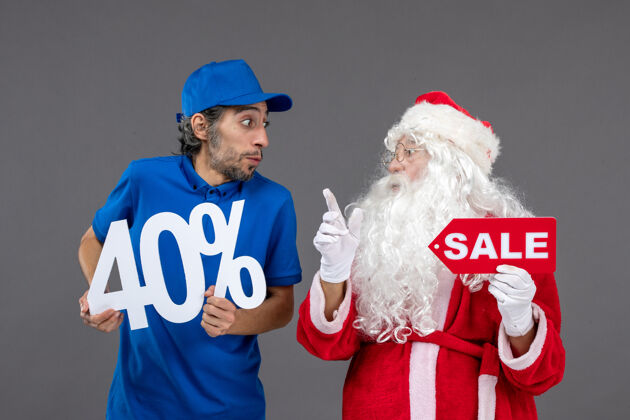 销售圣诞老人的正面图 灰色墙上的男性信使手持销售横幅人十二月快乐
