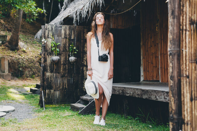 运动鞋亚洲热带度假的年轻美女 夏季风格 白色波西米亚裙 运动鞋 数码相机 旅行者 草帽 轻松 裙子女士嬉皮士