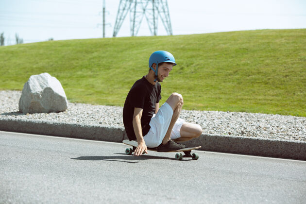 溜冰在阳光明媚的日子里 在城市街道上玩滑板的人穿着装备的年轻人在沥青路面上骑行和玩长板休闲活动 运动 极限 爱好和运动的概念城市游戏可怕