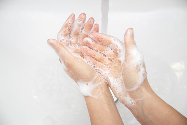 清洁特写：一个女人正在流水下洗手上的肥皂泡沫肥皂泡沫上
