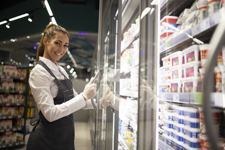 超市超市工作人员拿着食物站在冰箱旁的画像成人围裙有机