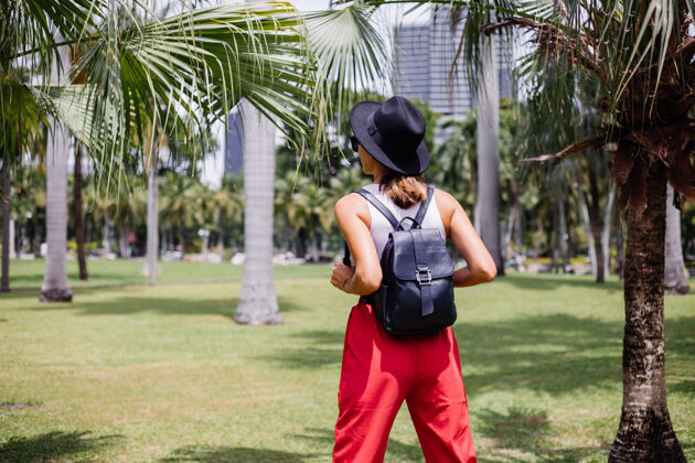 棕榈快乐女人背着背包环游曼谷 在绿草如茵的热带公园里享受美丽的晴天休闲树优雅