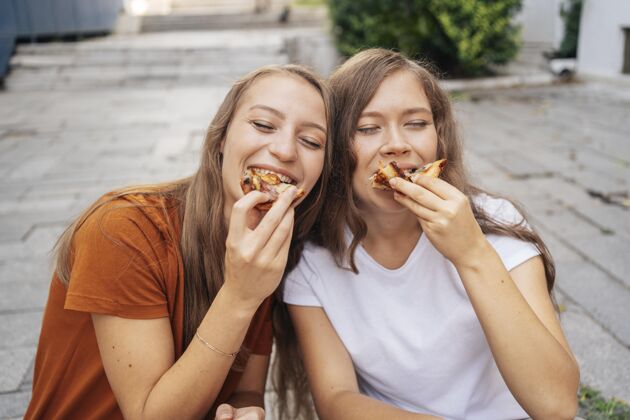 休息年轻女人一起在外面吃披萨高兴休闲社区