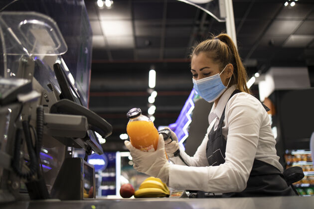 健康食品杂货店的收银员戴着防毒面具和手套扫描仪风险持有