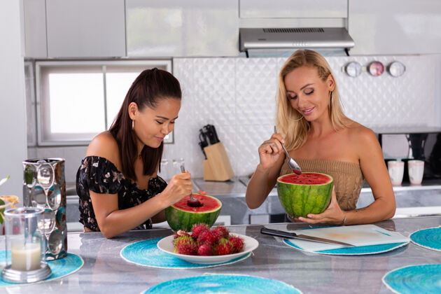 饮食两个女朋友在厨房吃西瓜和红毛丹热带水果水果吃有机