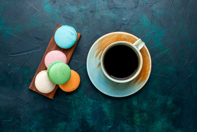 甜味在深蓝色的桌子上可以俯瞰一杯茶和法国马卡龙马克杯茶饮料