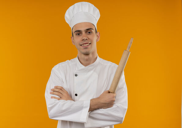 穿笑容可掬的男青年酷酷地穿着厨师制服手持擀面杖 双手交叉着复制空间抱手厨师