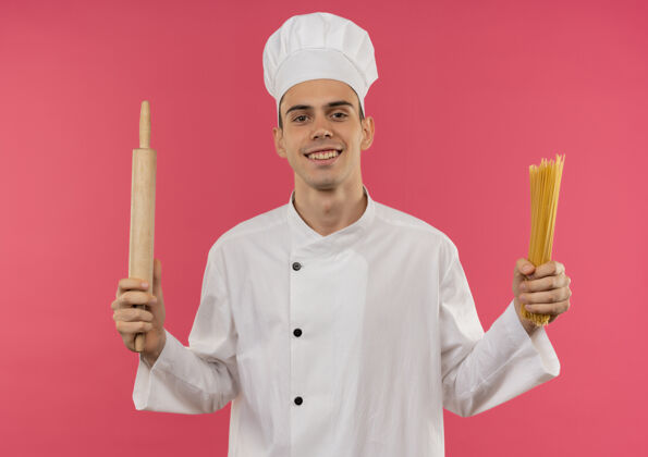 制服面带微笑的年轻男厨师穿着厨师制服拿着擀面杖和意大利面意大利面厨师男