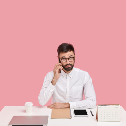 企业家严肃不刮胡子的聪明男人打电话给客户服务 在工作间隙打电话 穿着白衬衫 专注向上休息的人现代人衬衫