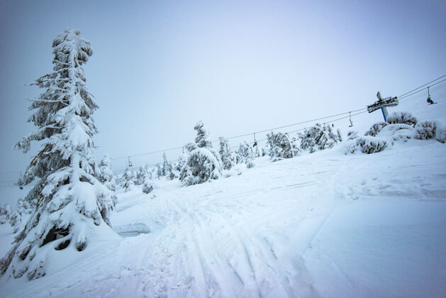 天气美丽的风景如画的带缆车的冬季斜坡位于多云的冬日山林之间的滑雪胜地乡村休息的概念复制空间季节景观冬天