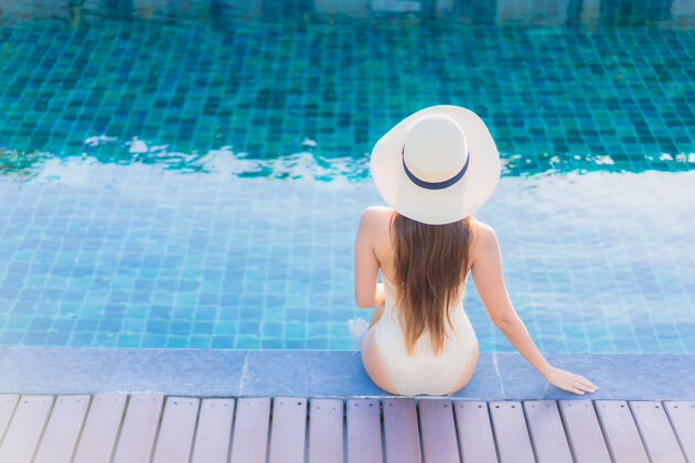 享受美丽的亚洲年轻女子在度假酒店的室外游泳池周围放松的肖像休息休闲放松