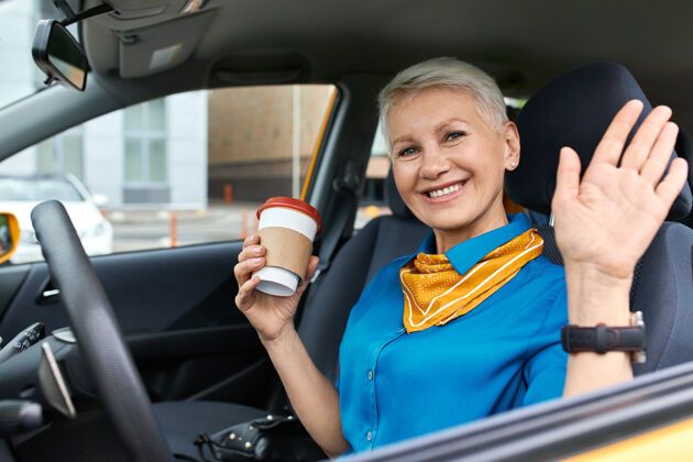 交通自信开朗的成熟女商人 金色短发 坐在驾驶座上 手里拿着一次性纸杯汽车保护交通