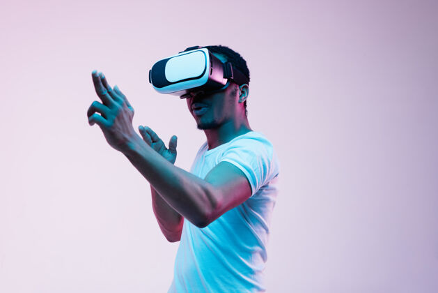 周末年轻人的指向和使用虚拟现实眼镜在霓虹灯的梯度模特游戏面部