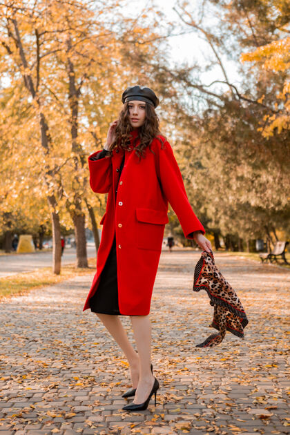 服装迷人时尚的微笑瘦削女子卷发漫步公园身着暖红色外套秋季时尚 街头风 头戴贝雷帽和豹纹围巾配饰年轻女士