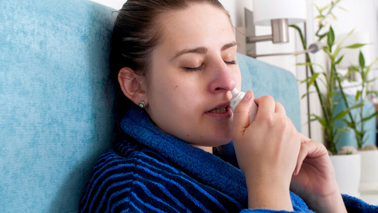 药物特写照片生病的妇女感冒使用鼻喷雾剂在鼻子房子悲伤组织