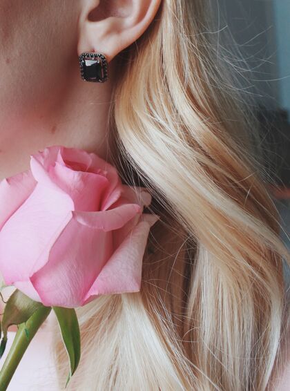 钻石垂直特写镜头 一个金发女性戴着一个黑色珍珠的耳环 手里拿着一朵粉红色的玫瑰珍珠项链奢侈品
