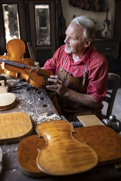 锯末高级木匠正在检查小提琴乐器 他要修理了木工工匠手持