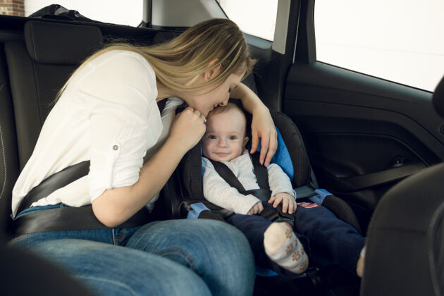 护理快乐的年轻母亲和她的孩子坐在后座上的画像小驾驶后代