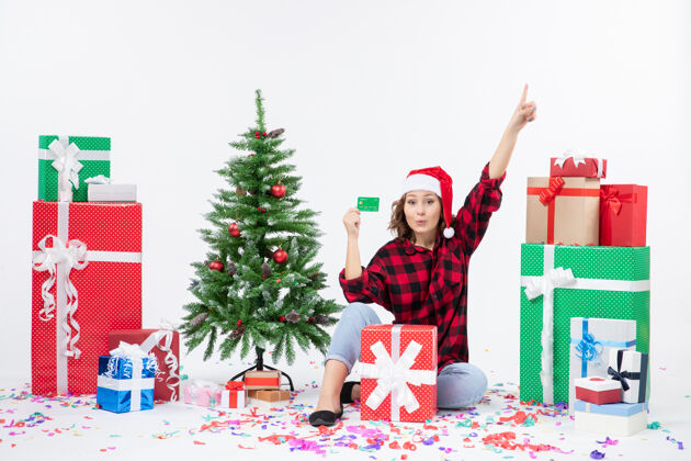 微笑前视图年轻女子围坐在一个白色的墙上拿着绿色银行卡的礼物圣诞快乐圣诞节快乐