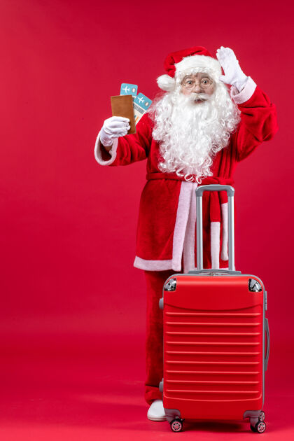 举行圣诞老人的前视图 带着包 拿着票 准备在红墙上旅行圣诞老人节日表情