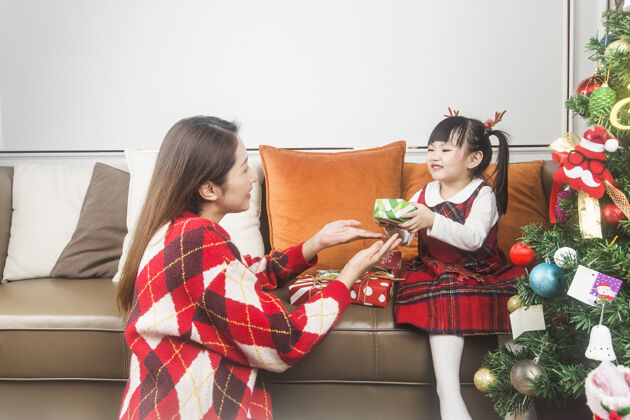 装饰快乐的妈妈和小女儿在家装饰圣诞树和礼物女儿节日女孩