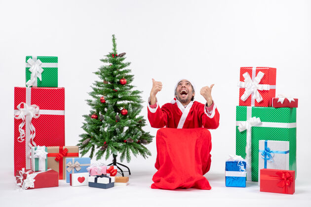 圣诞老人情绪激动 心满意足的年轻人装扮成圣诞老人 拿着礼物 在白色背景上装饰圣诞树圣诞圣诞树高尔夫球手