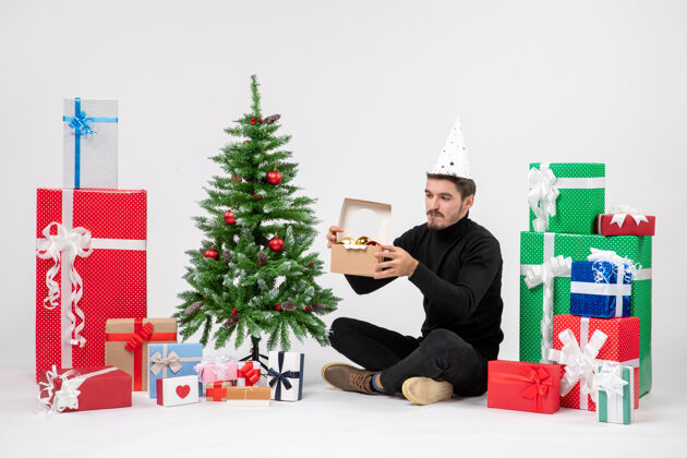 礼物正面图：年轻人围坐在节日礼物旁边 拿着一个白色墙上的玩具包礼物节日节日