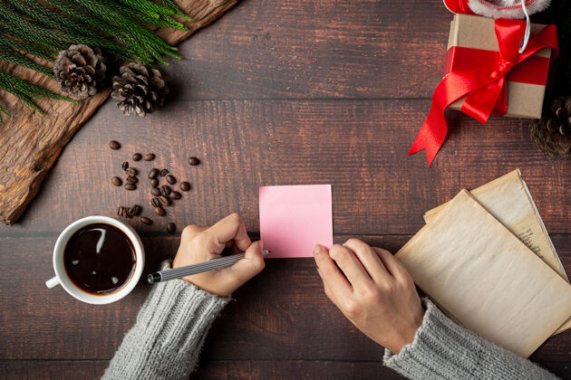 新年一杯咖啡和礼盒放在女士的手旁写着贺卡包装盒子礼品盒