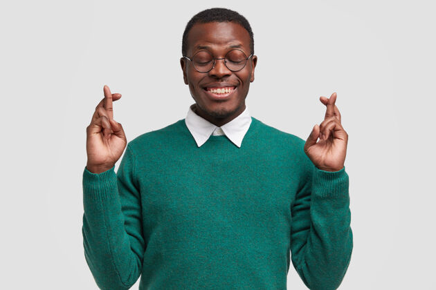 眼镜微笑的美国黑人男子祈祷他的愿望得到实现 交叉手指 祝好运考试眼镜大学