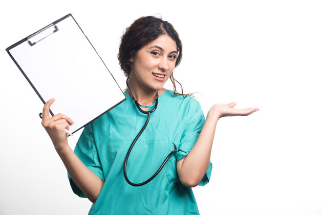 成人女医生在白色背景上用钢笔和听诊器展示空剪贴板高质量照片微笑年轻剪贴板