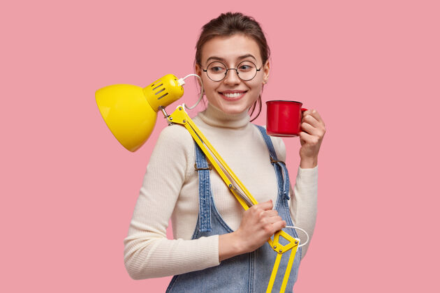 眼镜笑容可掬的女记者在家工作 端着黄色台灯和酒杯 神采奕奕 喝着咖啡休息服装文案青少年