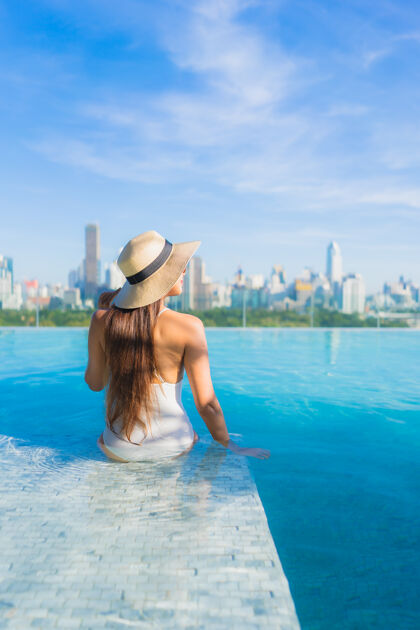 城市美丽的亚洲年轻女子在户外游泳池周围放松 城市景色尽收眼底比基尼游泳池塔楼